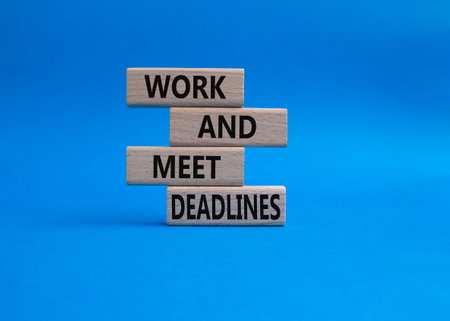 Work and deadline symbol. Concept words Work and meet deadlines on wooden blocks. Beautiful blue background. Business and Work and meet deadlines concept. Copy space.の写真素材