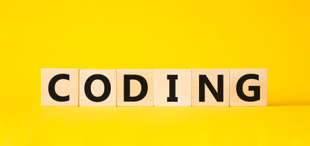 Coding symbol. Concept word Coding on wooden cubes. Beautiful yellow background. Business and Coding...