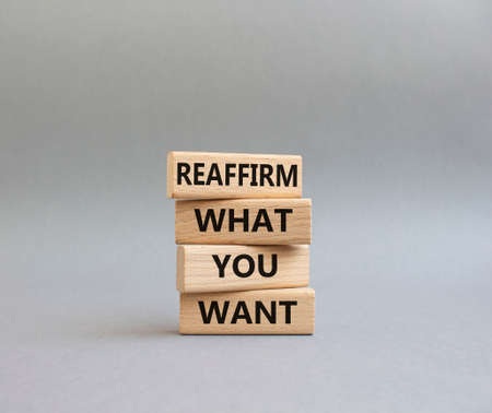 Goals symbol. Wooden blocks with words 'Reaffirm what you want'. Beautiful grey background. Business and 'Reaffirm what you want' concept. Copy space.の写真素材