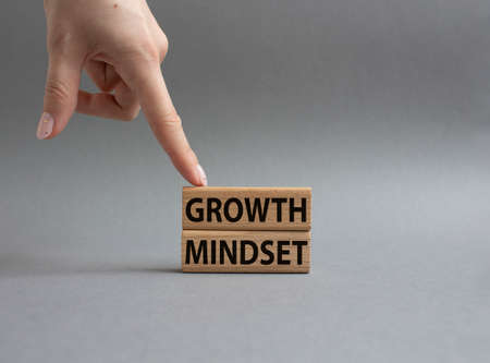 Growth Mindset symbol. Concept word Growth Mindset on wooden blocks. Beautiful gray background. businessman hand. Business and Growth Mindset concept. copy spaceの写真素材