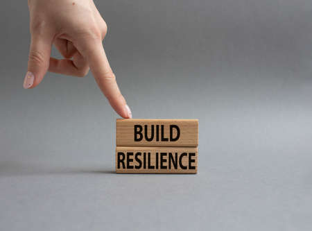 Build strength symbol. Wooden blocks with words Build resilience. Beautiful gray background. businessman hand. Business and Build resilience concept. copyspace.の写真素材