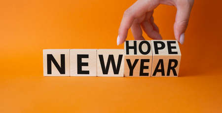 new year new hope symbol. Hand turns cubes and changes the words new year to new hope. Beautiful orange background. businessman hand. business concept. copy spaceの写真素材