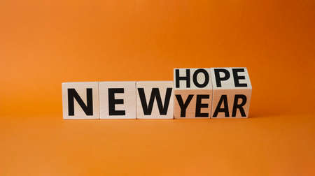 new year new hope symbol. Turned cubes with words new year and new hope. Beautiful orange background. business concept. copy spaceの写真素材