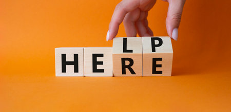 Help is here symbol. Businessman hand Turnes cubes and changes word Here to Help. beautiful orange background. Business and Help is here concept. copy spaceの写真素材