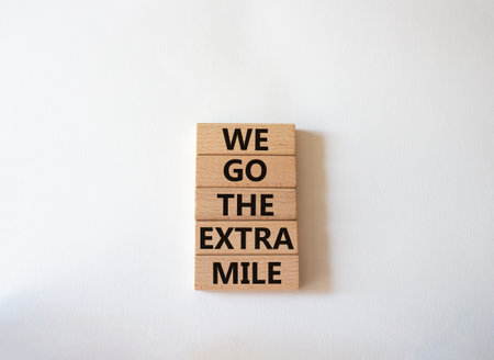 We go the extra mile symbol. Wooden blocks with words We go the extra mile. Beautiful white background. Business and We go the extra mile concept. copyspace.の写真素材