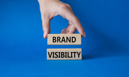 Brand visibility symbol. Wooden blocks with words Brand visibility. beautiful blue background. businessman hand. Business and brand visibility concept. copyspace.の写真素材
