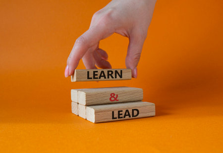 Learn and lead symbol. Concept words Learn and lead on wooden blocks. Beautiful orange background. businessman hand. Business and Learn and lead concept. copyspace.の写真素材