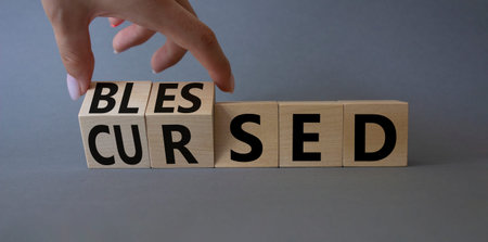 Blessed vs Cursed word symbol. Businessman Hand turns cubes with word Cursed and changes it to word...