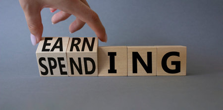Earning and Spending symbol. businessman hand. Turned cubes with words Earning and Spending....