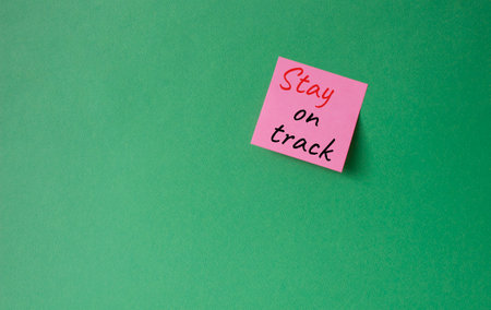 Stay on track symbol. Concept words words Stay on track on pink steaky note. beautiful green background. Business and Stay on track concept. copyspace.の写真素材