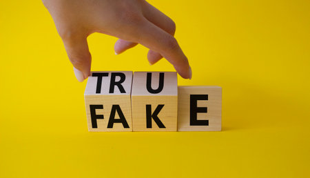 True vs Fake symbol. Businessman Hand turns cubes and changes word Fake to True. beautiful yellow background. Business and True vs Fake concept. copy spaceの写真素材