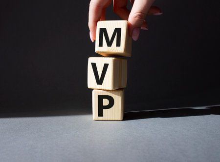 MVP - Most Valuable Player symbol. Wooden cubes with words MVP. businessman hand. Beautiful gray background. Business and MVP concept. copyspace.の写真素材