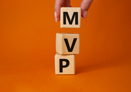 MVP - Most Valuable Player symbol. Wooden cubes with words MVP. businessman hand. beautiful orange background. Business and MVP concept. copyspace.の写真素材