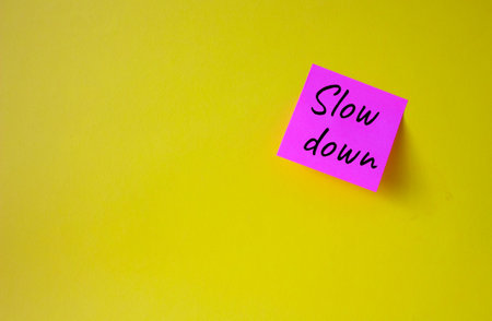 Slow down symbol. Pink steaky note with words Slow down. beautiful yellow background. Business and...