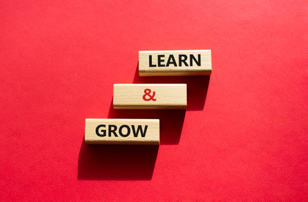Learn and grow symbol. Concept words Learn and grow on wooden blocks. Beautiful red background. Business and Learn and grow concept. Copy space.の写真素材