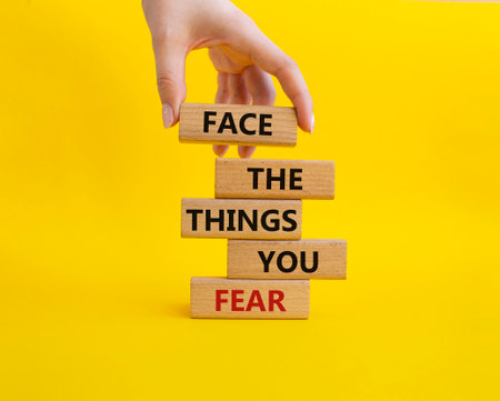 Face the things you fear symbol. Wooden blocks with words Face the things you fear. Beautiful yellow background. businessman hand. Business and Face the things you fear concept. copyspace.の写真素材
