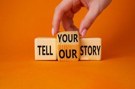 Tell Your or Our story symbol. Businessman hand turns wooden cubes and changes the words Tell your story to Tell our story. beautiful orange background. business concept. copy spaceの写真素材