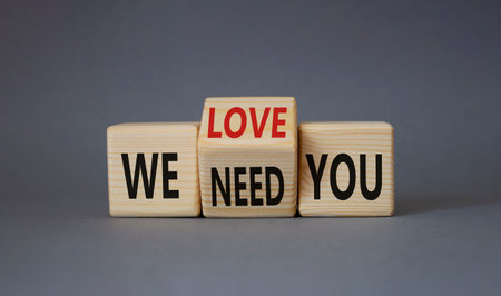 We love and need You symbol. Turned wooden cubes with words We need you and We love you. Beautiful gray background. Business and We love and need You concept. copy spaceの写真素材