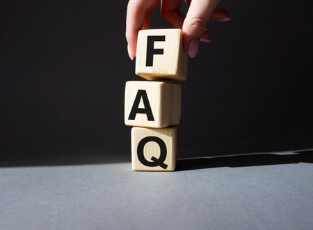 FAQ - Frequently Asked Questions symbol. Concept word FAQ on wooden cubes. businessman hand. Beautiful gray background. Business and FAQ concept. copyspace.の写真素材