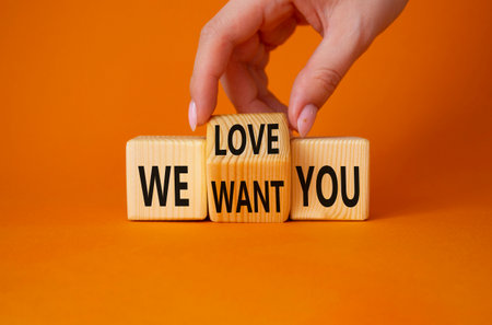 We love and want you symbol. Businessman Hand turns cubes and changes word We want you to We love you. Beautiful orange background. Business and We love and want You concept. copy spaceの写真素材