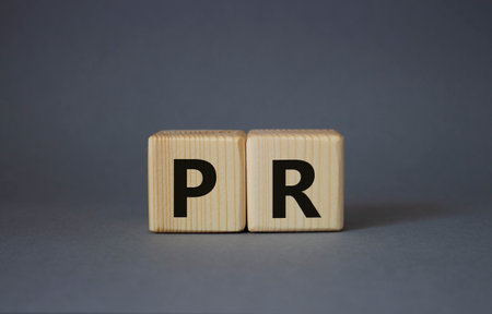 PR - Public Relations symbol. Concept word PR on wooden cubes. Beautiful gray background. Business and PR concept. copyspace.の写真素材