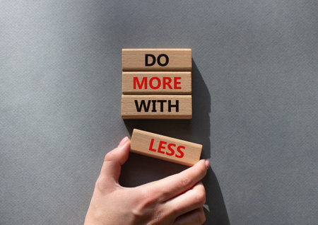 Do more with less symbol. Concept words Do more with less on wooden blocks. Beautiful gray background. businessman hand. Business and Do more with less concept. copyspace.の写真素材