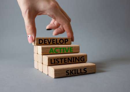 Listening skills symbol. Concept word Develop active listening skills on wooden blocks. Beautiful gray background. businessman hand. Business and Develop active listening skills concept. copy spaceの写真素材
