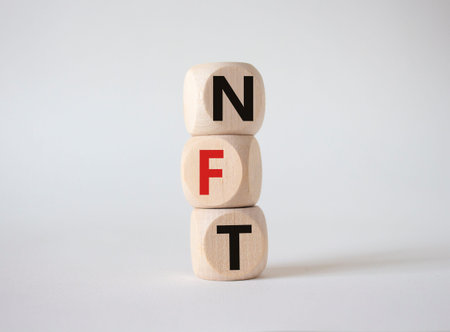NFT - non-fungible token symbol. Concept word NFT on wooden cubes. Beautiful white background....