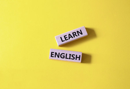 Learn English symbol. Wooden blocks with words Learn English. beautiful yellow background. Business and Learn English concept. copyspace.の写真素材