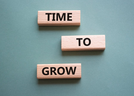 Time to Grow symbol. Concept word Time to Grow on wooden blocks. Beautiful gray green background....