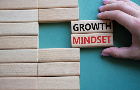 Growth mindset symbol. Concept word Growth Mindset on wooden blocks. businessman hand. Beautiful gray green background. Business and Growth Mindset concept. copy spaceの写真素材