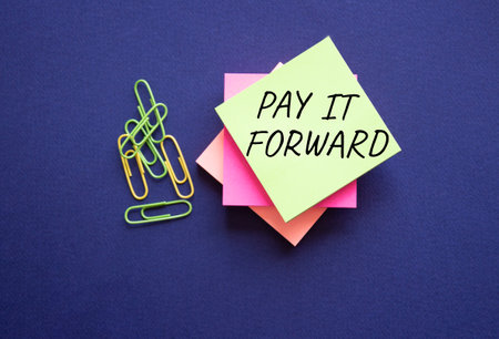 Pay it forward symbol. Concept words Pay it forward on yellow steaky note with paper clips. beautiful pink background. Business and Pay it forward concept. copyspace.の写真素材