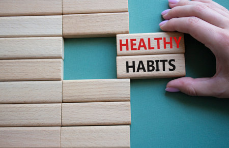 Healthy habits symbol. Concept word Healthy habits on wooden blocks. businessman hand. Beautiful gray green background. Business and Healthy habits concept. copy spaceの写真素材