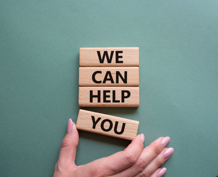 We can help you symbol. Concept words We can help you on wooden blocks. Beautiful gray green background. businessman hand. Business and We can help you concept. copy spaceの写真素材