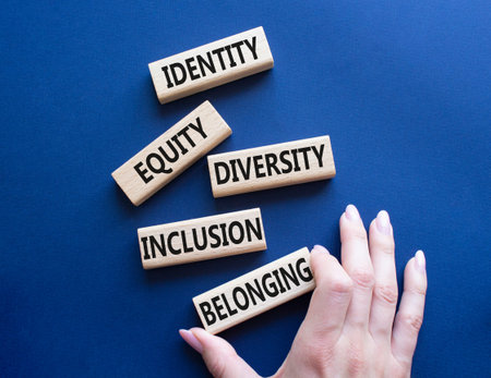 Identity Equity Diversity Inclusion Belonging symbol. Concept words Identity Equity Diversity Inclusion Belonging on wooden blocks. businessman hand. Beautiful deep blue background. business conceptの写真素材