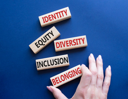 Identity Equity Diversity Inclusion Belonging symbol. Concept words Identity Equity Diversity Inclusion Belonging on wooden blocks. businessman hand. Beautiful deep blue background. business conceptの写真素材