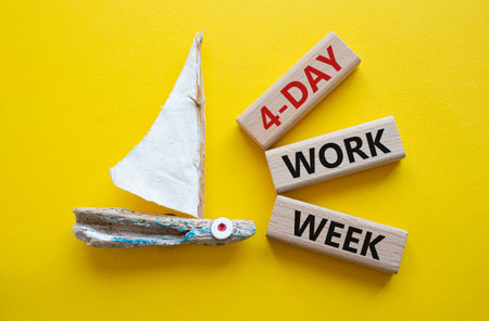 4-day work week symbol. Concept words 4-day work week on wooden blocks. Beautiful yellow background with boat. Business and 4-day work week concept. copy spaceの写真素材