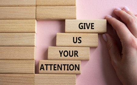 Attention symbol. Concept word Give us your attention on wooden blocks. beautiful pink background....