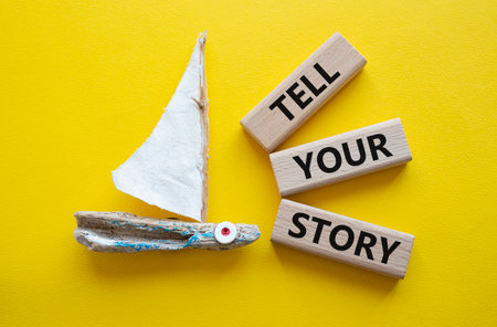 Tell your story symbol. Wooden blocks with words Tell your story. Beautiful yellow background with boat. Business and Tell your story concept. copyspace.の写真素材