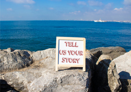 Tell us your story symbol. Concept words Tell us your story on white chalk blackboard. Beautiful sea background. Business and Tell us your story concept. Copy space.の写真素材