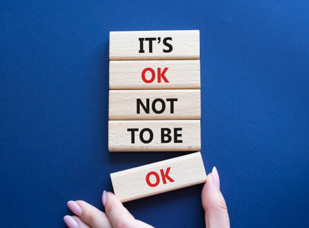 Mental Health symbol. Wooden blocks with words It is ok not to be ok. Doctor hand. Beautiful deep blue background. Mental Health concept. Copy space.の写真素材