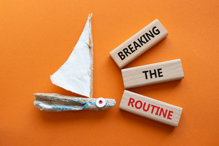 Breaking the Routine week symbol. Concept words Breaking the Routine on wooden blocks. Beautiful orange background with boat. Business and Breaking the Routine concept. Copy spaceの写真素材