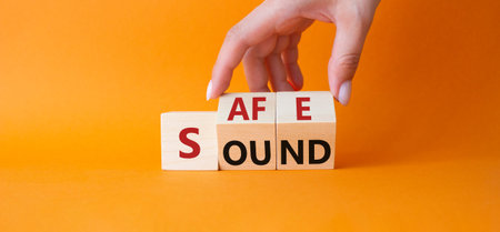 Safe and Sound symbol. Businessman hand Turns cubes with words Safe and Sound. Beautiful orange...