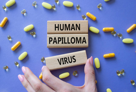 Human Papilloma Virus symbol. Concept word Human Papilloma Virus on wooden blocks. Doctor hand. Beautiful pink background with pills. Medicine and Human Papilloma Virus concept. Copy spaceの写真素材