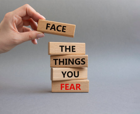Face the things you fear symbol. Wooden blocks with words Face the things you fear. Beautiful gray background. Businessman hand. Business and Face the things you fear concept. Copy space.の写真素材