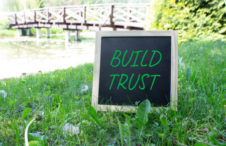 Build trust symbol. Build trust on chalk blackboard. Beautiful meadow background. Business and Build...