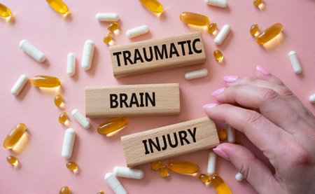 Traumatic Brain Injury symbol. Concept words Traumatic Brain Injury on wooden blocks. Beautiful pink background with pills. Doctor hand. Healthcare and Traumatic Brain Injury concept. Copy space.の写真素材