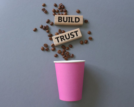 Build trust symbol. Wooden blocks with words Build trust. Beautiful gray background with coffee cup. Business and Build trust concept. Copy space.の写真素材