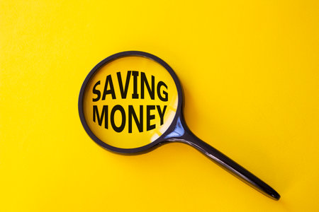 Saving Money symbol. Concept words Saving Money on magnifying glass. Beautiful yellow background. Business and Saving Money concept. Copy space.の写真素材