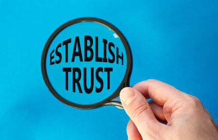 Establish trust symbol. Magnifying Glass with Concept word Establish trust. Beautiful blue background. Businessman hand. Business and Establish trust concept. Copy spaceの写真素材